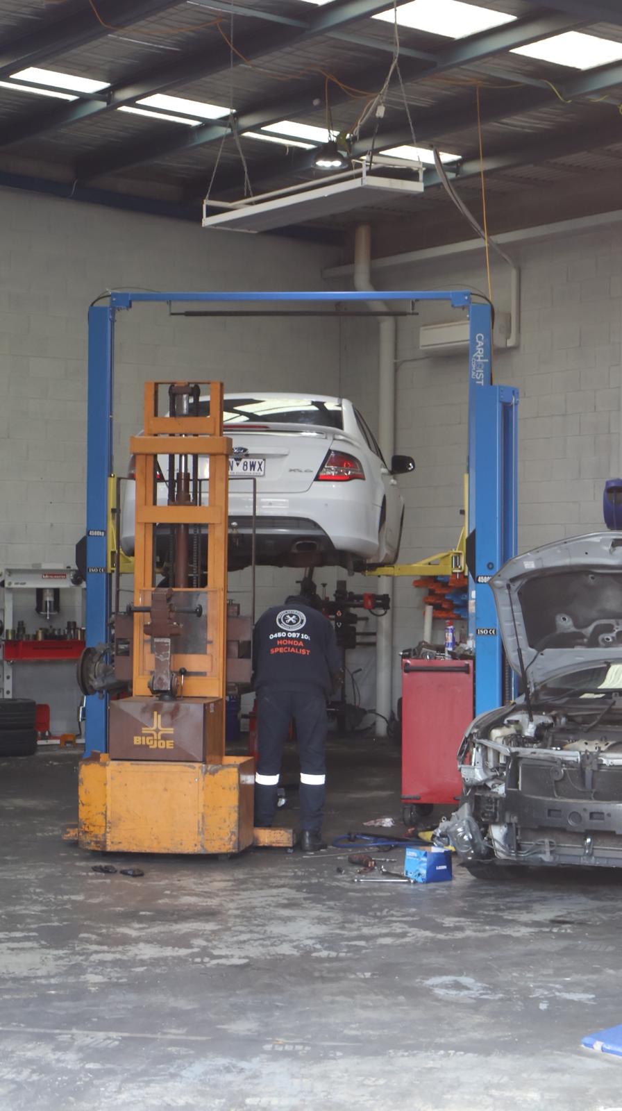 Sharp Autoworks two-post hoist workshop with a vehicle raised for servicing
