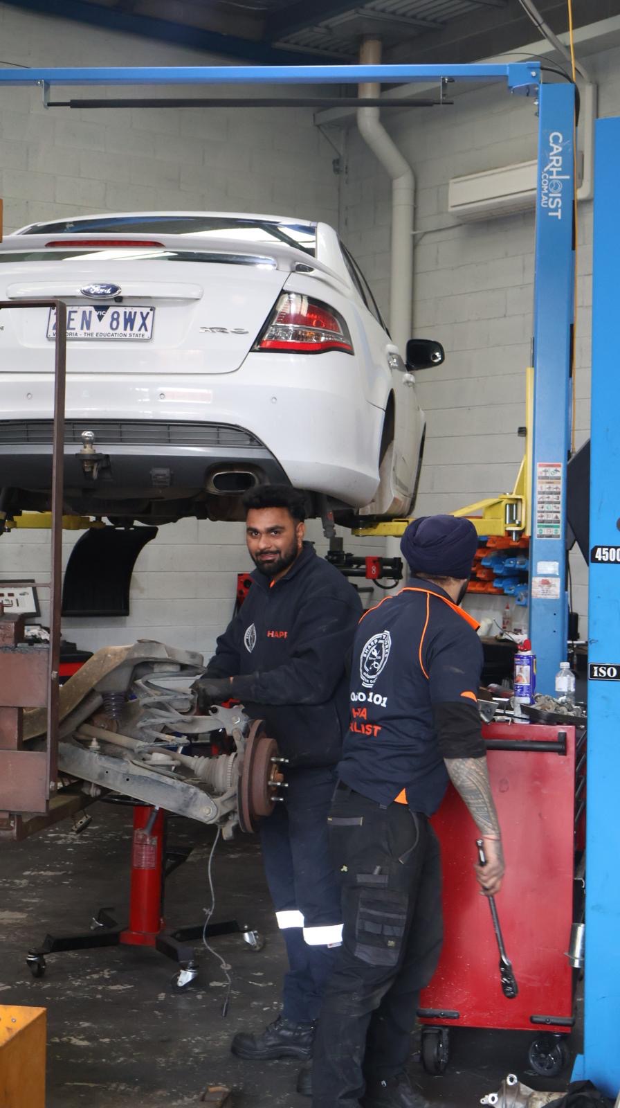 Sharp Autoworks mechanics working on a vehicle's rear suspension